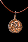 Ca. 100-300 AD.
Fashioned from bronze, this circular pendant features a flat section body and is equipped with a suspension loop, allowing it to be wo...