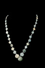 Ca. 1-300 AD.
A restrung necklace composed of circular sherds crafted from lustrous greenish-blue glass, each possessing a mesmerizing shimmering pati...