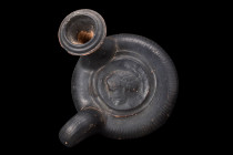 Ca. 500-400 BC.
A terracotta guttos, adorned with a lustrous black glaze, presents its distinctive form. This Greek vessel features a long spout with ...