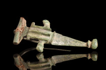 Ca. 1st century AD.
A bronze fibula with a triangular-shaped footplate that anchors the piece. This footplate culminates in a distinctive knob, its ro...