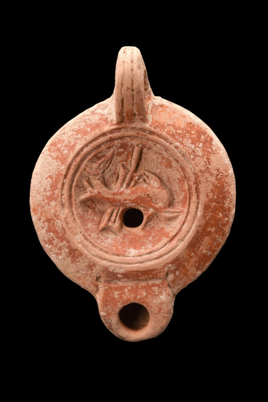 Ca. 1-100 AD.
A terracotta oil lamp boasting a distinctive reddish hue and a cha...