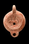 Ca. 1-100 AD.
A terracotta oil lamp boasting a distinctive reddish hue and a charming, recessed tondo adorned with a dolphin in front of the rudder. T...