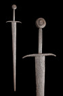 Ca. 1300-1350 AD.
An iron sword featuring a raised boss pommel, a long flat-section hilt, and a cross guard with curved tips on the ends towards the b...