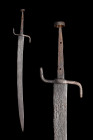 Ca. 1300-1400 AD.
Falchion, with a broad single-edged, curved blade, a guard formed of a combined forward quillon and knuckle bow, each with a flatten...