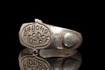 Ca. 600 AD.
A silver finger ring with a flat-section hoop that gracefully flares to form a delicate bezel. Notably, the shoulders of the ring are ador...