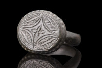 Ca. 1100-1400 AD.
A bronze finger ring featuring a round hoop, and a large oval-shaped bezel, adorned with an engraved central depiction of the Star o...