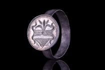 European, ca. 1100-1400 AD.
A silver ring with a flat-section circular band, and an applied circular bezel decorated with an incised coat of arms topp...