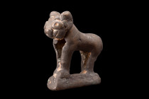 Ca. 1100-1200 AD.
A bronze figurine depicting of a lion in a profile stance positioned atop an integral base. The lion's visage is captivating, charac...
