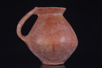 Ca. 3rd Millennium BC.
A Holy Land jug set on a low ring foot with a squat, globular body and a long vertical handle that begins at the widest part of...