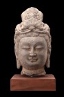 Ca. 581-618 AD.
A stone head of Buddha with elaborate coiffured hair curls under a richly ornamented headdress. He is characterised by his arched bro...