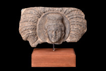 Ca. 200-300 AD.
A stone schist panel featuring a central relief depicting the head of Buddha, showcasing distinctive iconographic elements prevalent i...