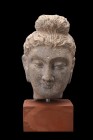Ca. 200-400 AD.
A schist head of Buddha, with characteristic topknot (Ushnisha) and elongated, pendular ears. His forehead is ornamented with an urna...
