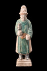 Ca. 1368-1644 AD or later .
A glazed terracotta mingqi depicting a standing attendant on a tiered, integral base. He is portrayed in a noble and digni...