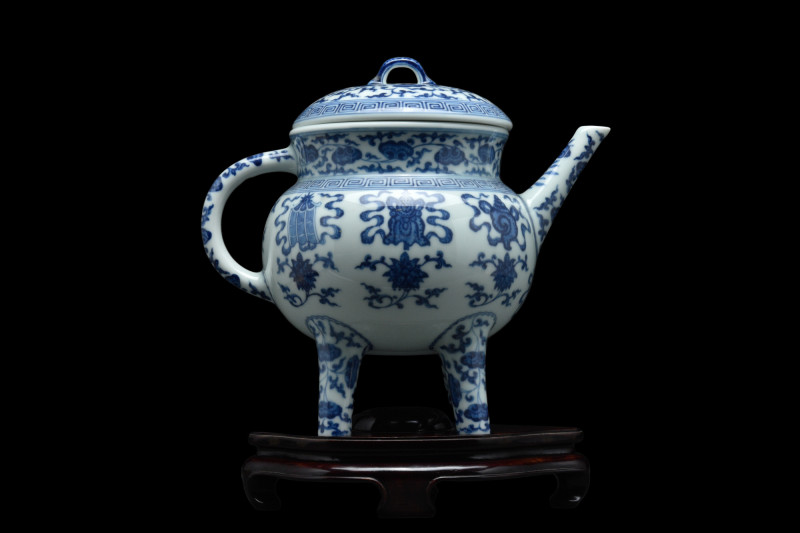 .
A white and blue porcelain ewer with a squat body resting on four cylindrical ...