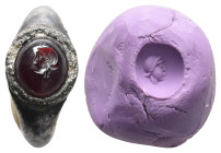 Hellenistic silver finger ring with garnet in bezel (c. 3rd century BC).
Convex garnet gem, set in a silver ring, engraved in intaglio with the male h...