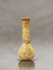 Presenting an antique Roman pale glass flask of timeless beauty. This captivating artifact features a tall cylindrical neck and a wide flat rim, harmo...