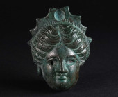 A LARGE ROMAN BRONZE APPLIQUE WITH A FEMALE HEAD Circa 1st-2nd century AD. Applique in the form of a female head wearing stephane; the eyes and the ce...
