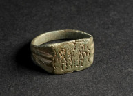 A BYZANTINE BRONZE RING WITH TWO VICTORIES Circa 6th-9th century AD. With rectangular bezel depicting two highly stylised winged figures, between them...