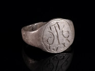 A MEDIEVAL SILVER RING WITH ORNAMENTAL DESIGN Circa 12th-13th century AD. Oval bezel with engraved design, hoop with overlapping ends. Ring size 51 (E...