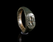 A BYZANTINE BRONZE RING WITH A FIGURE Circa 6th-9th century AD. With a flattened oval bezel depicting a highly stylised human figure framed by a punch...