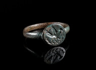 LATE ANTIQUE/EARLY BYZANTINE BRONZE RING WITH A DOVE Circa 4th-6th century AD. With round bezel depicting a flying dove between two branches; remains ...