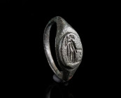 A ROMAN BRONZE RING DEPICTING A STANDING GODDESS Circa 3rd century AD. Ring with offset shoulders and raised oval bezel showing a goddess with sceptre...
