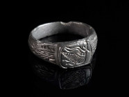 A BYZANTINE BRONZE RING WITH A BIRD Circa 6th-9th century AD. The shoulders decorated with elaborate incised design; the rectangular, offset bezel dep...