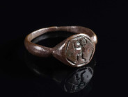 A LATE ROMAN/EARLY BYZANTINE BRONZE RING WITH A WARRIOR Circa 4th-6th century AD. With an offset hexagonal bezel depicting a warrior or hunter advanci...