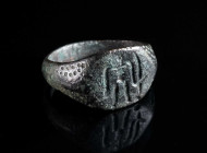 A MEDIEVAL BRONZE RING WITH A STANDING FIGURE Circa 12th-14th century AD. The shoulders decorated with a dotted design; the bezel features a highly st...