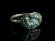 A GREEK BRONZE RING WITH A COCKEREL Circa 3rd-1st century BC. With an oval bezel depicting a cockerel with ears of corn(?). Ring size 51 (EU)

Ex pr...