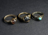 A GROUP OF THREE BYZANTINE BRONZE RINGS WITH GLASS STONES Circa 12th-14th century AD. With coloured cabochon glass stones in a claw setting. Ring size...