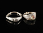 TWO ROMAN SILVER RINGS Circa 3rd century AD. One with an oval undecorated bezel, the other set with a carnelian intaglio depicting a leaf(?). Worn, wi...