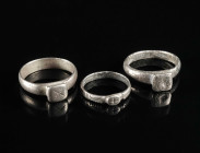 THREE LATE ROMAN/EARLY BYZANTINE SILVER RINGS Circa 4th-6th century AD. Two with a square bezel, one with an oval bezel; two decorated with a cross, o...