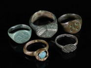 A GROUP OF FIVE MEDIEVAL/EARLY MODERN BRONZE RINGS Circa 12th-16th century AD. Four with decorated bezel; one with coloured cabochon glass stone in a ...