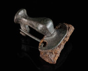 A LARGE ROMAN BRONZE KNEE BROOCH Circa 2nd-3rd century AD. With facetted arched bow leading to a pelta-shaped head plate; spring and pin made of bronz...