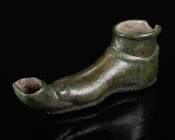 A ROMAN BRONZE OIL LAMP IN THE SHAPE OF FOOT WITH SANDAL Circa 1st-2nd century AD. Small cast-bronze oil lamp in the shape of a right foot wearing a s...