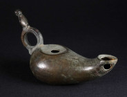 AN EARLY BYZANTINE BRONZE OIL LAMP Circa 5th-6th century AD. With elongated body and a loop-handle; spout corroded through at one spot. L 10.2 cm

P...