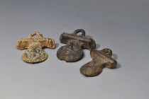 ARQUEOLOGÍA. ROMA. Lote de 3 apliques de asa de sítula (ss.I-IV d.C.). Bronce. Longitud de 5 a 6 cm.