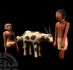 Egyptian Painted Wooden Model of a Cow Giving Birth, Together with Two Figures