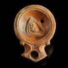 Roman Oil Lamp with Theatre Mask
1st-2nd century CE
Clay, 88 mm
Showing a theatre-mask beside a club.
Very fine condition. Small hole on the stand...