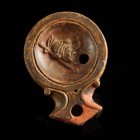 Roman Oil Lamp with Theatre Mask
1st-2nd century CE
Clay, 89 mm
Showing a theatre-mask beside a stick.
Very fine condition. The spout has been res...