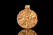 GREEK HELLENISTIC GOLD SUN PENDANT

 Ca. 4th century BC
 A gold sun pendant featuring a flat circular shape with a large suspension loop. The surfa...