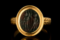 ROMAN BLOODSTONE INTAGLIO WITH DIOSCURI IN GOLD RING 

 Ca. AD 100-300
 A large oval-shaped bloodstone intaglio showcasing an intricate engraving o...