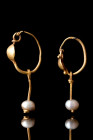 ROMAN MATCHED PAIR OF GOLD EARRINGS WITH PEARLS

 Ca. AD 100-200
 A pair of gold earrings, each of round-section wire tapering at one end and culmi...