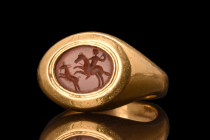 RARE ROMAN GOLD RING WITH CARNELIAN INTAGLIO DEPICTING A HUNTING SCENE - HEAVY GOLD

 Ca. AD 100-300
 A rare, heavy gold signet ring composed of a ...