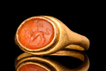 ROMAN GOLD RING WITH CARNELIAN INTAGLIO OF CUPID RIDING A LION

 Ca. AD 200
 A gold finger ring composed of a flat-section hoop with a raised ellip...