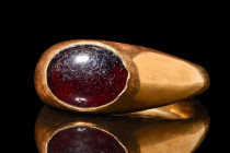 ROMAN GOLD RING WITH GARNET CABOCHON

 Ca. AD 400
 A finger ring composed of a hollow gold hoop, gradually expanded to create a bezel cell designed...