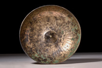 ROMAN BRONZE BOWL

 Ca. AD 100-300
 A bronze libation bowl featuring an hemispherical body with a raised, conical projection at the centre and an a...