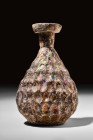 ROMAN GLASS FLASK

 Ca. AD 100-300
 A glass flask with beautiful iridescence. It features a piriform body, flattened base, short tubular neck, and ...