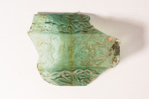 ROMAN GLASS FRAGMENT

 Ca. AD 100 - 300 
 A glass fragment with mould-blown shape, possibly a sherd from a vase or two-handled cup. The sherd is de...